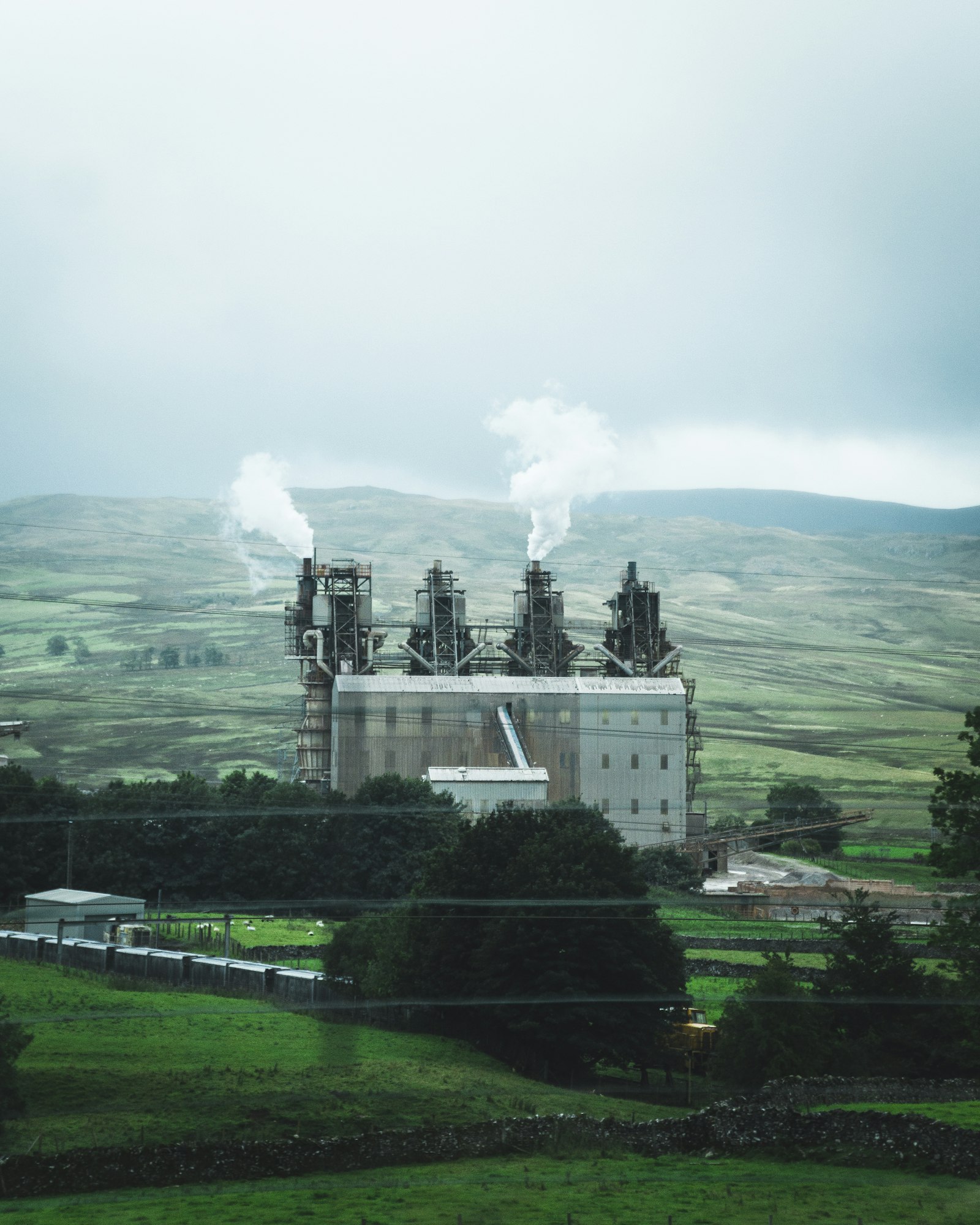 Fábrica industrial em meio a paisagem verde, ilustrando licenciamento ambiental
